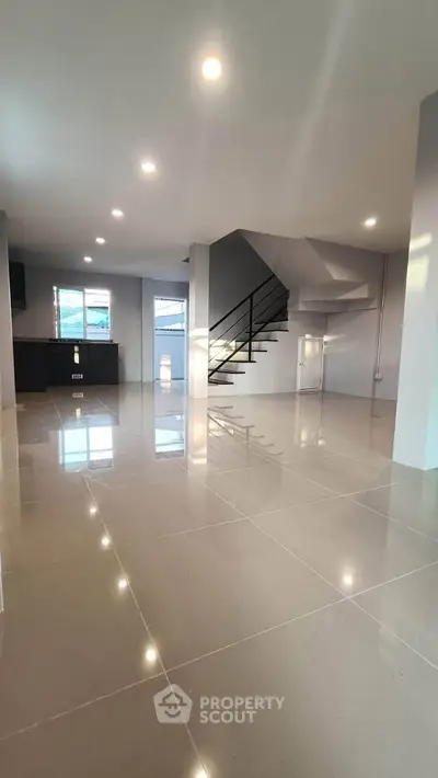 Spacious modern living room with sleek staircase and glossy tile flooring