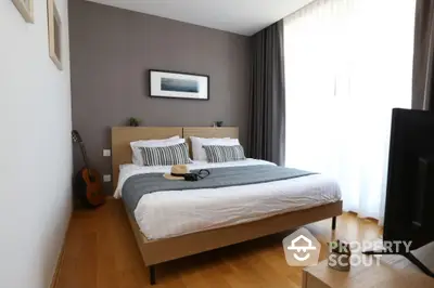 Modern bedroom with stylish decor and natural light, featuring a cozy bed and wooden flooring.