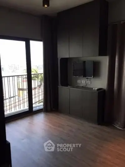 Modern living room with large window and balcony access in urban apartment.