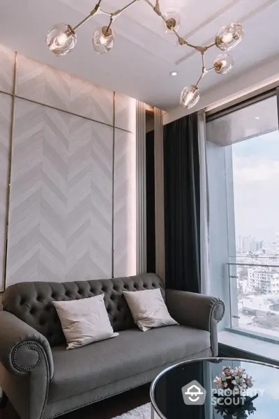 Elegant living room with chesterfield sofa, chic modern lighting, herringbone wall pattern, and panoramic city views through floor-to-ceiling windows.