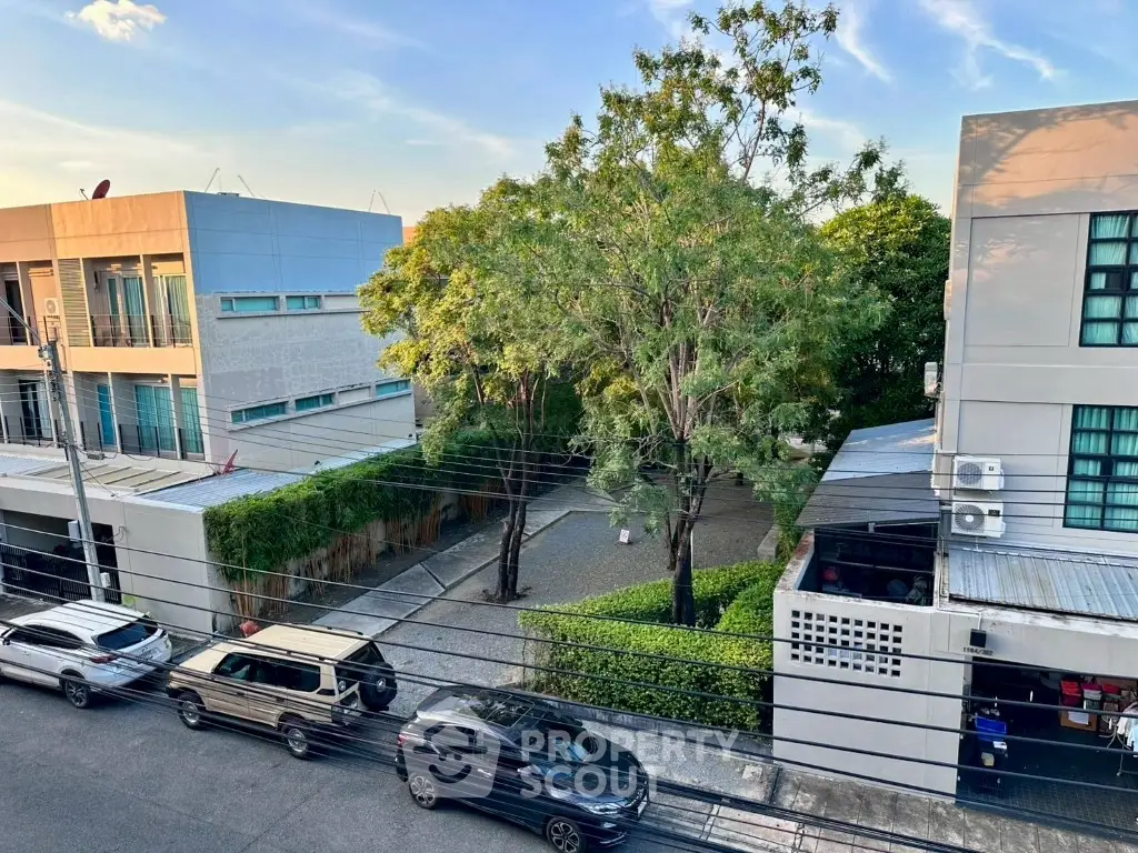 Modern residential street view with parked cars and lush greenery