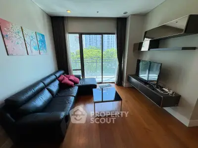 Modern living room with sleek black leather sofa and large window view