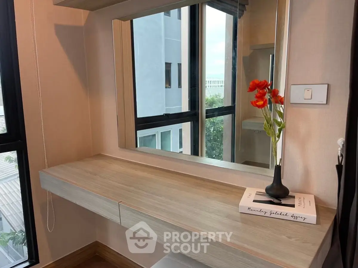 Modern interior with stylish vanity and large mirror in a well-lit room, featuring a decorative vase with flowers.
