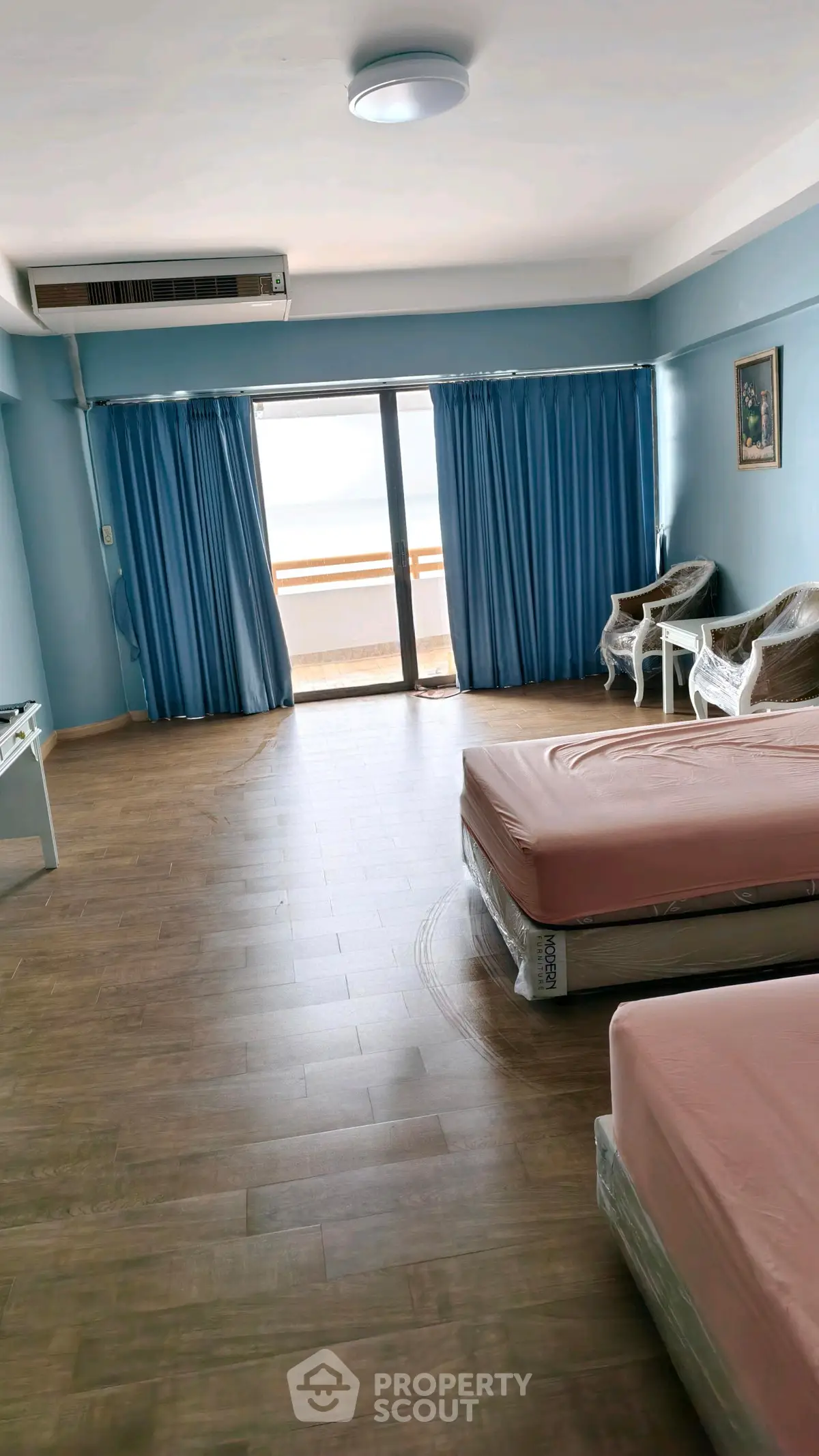 Spacious bedroom with balcony access and ocean view, featuring twin beds and elegant seating area.