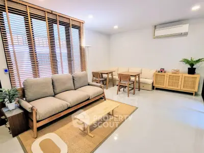 Modern living room with cozy sofa, wooden blinds, and minimalist decor.