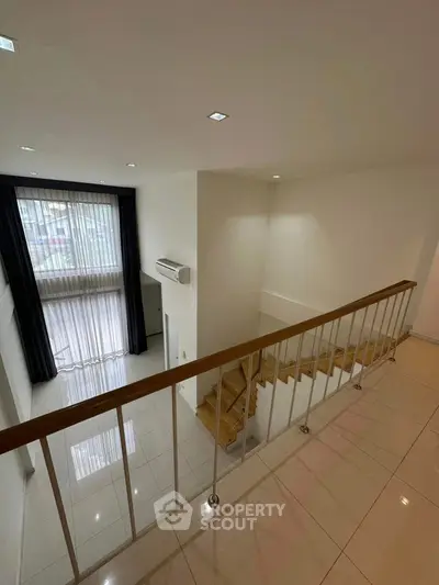 Spacious modern duplex with elegant staircase and large windows for natural light.