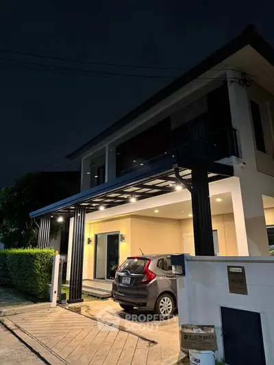 Modern two-story house with carport and night lighting, showcasing contemporary architecture and inviting ambiance.