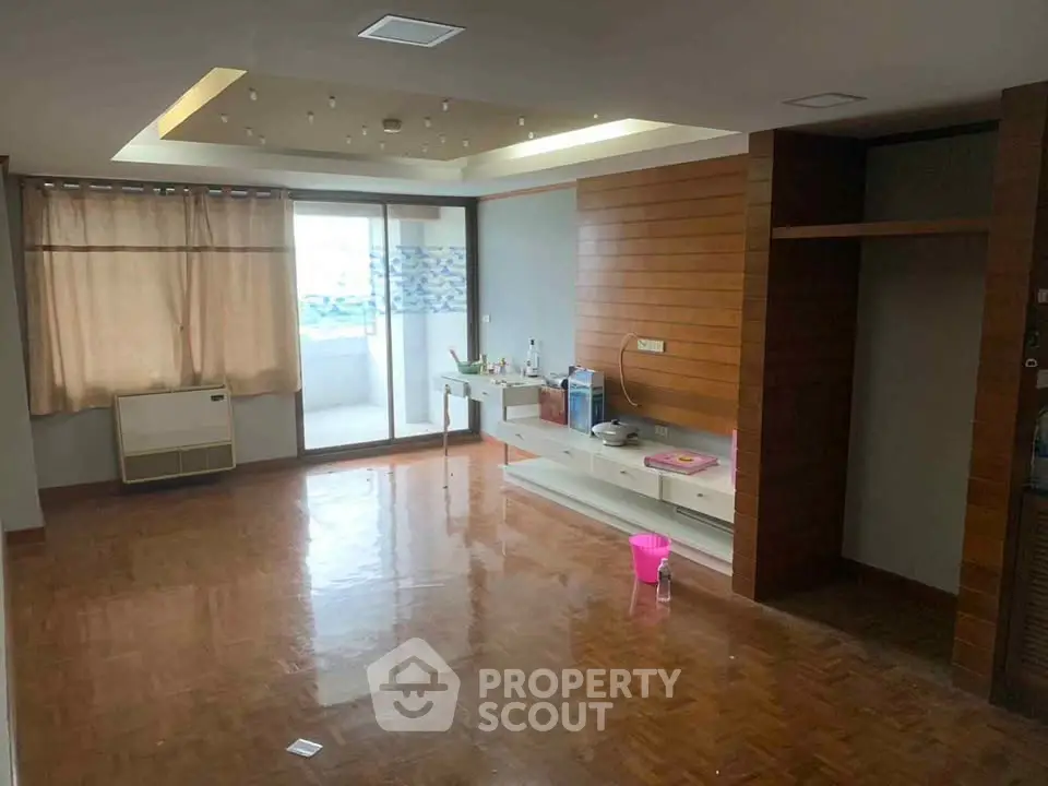 Spacious living room with wooden flooring and balcony access in modern apartment.
