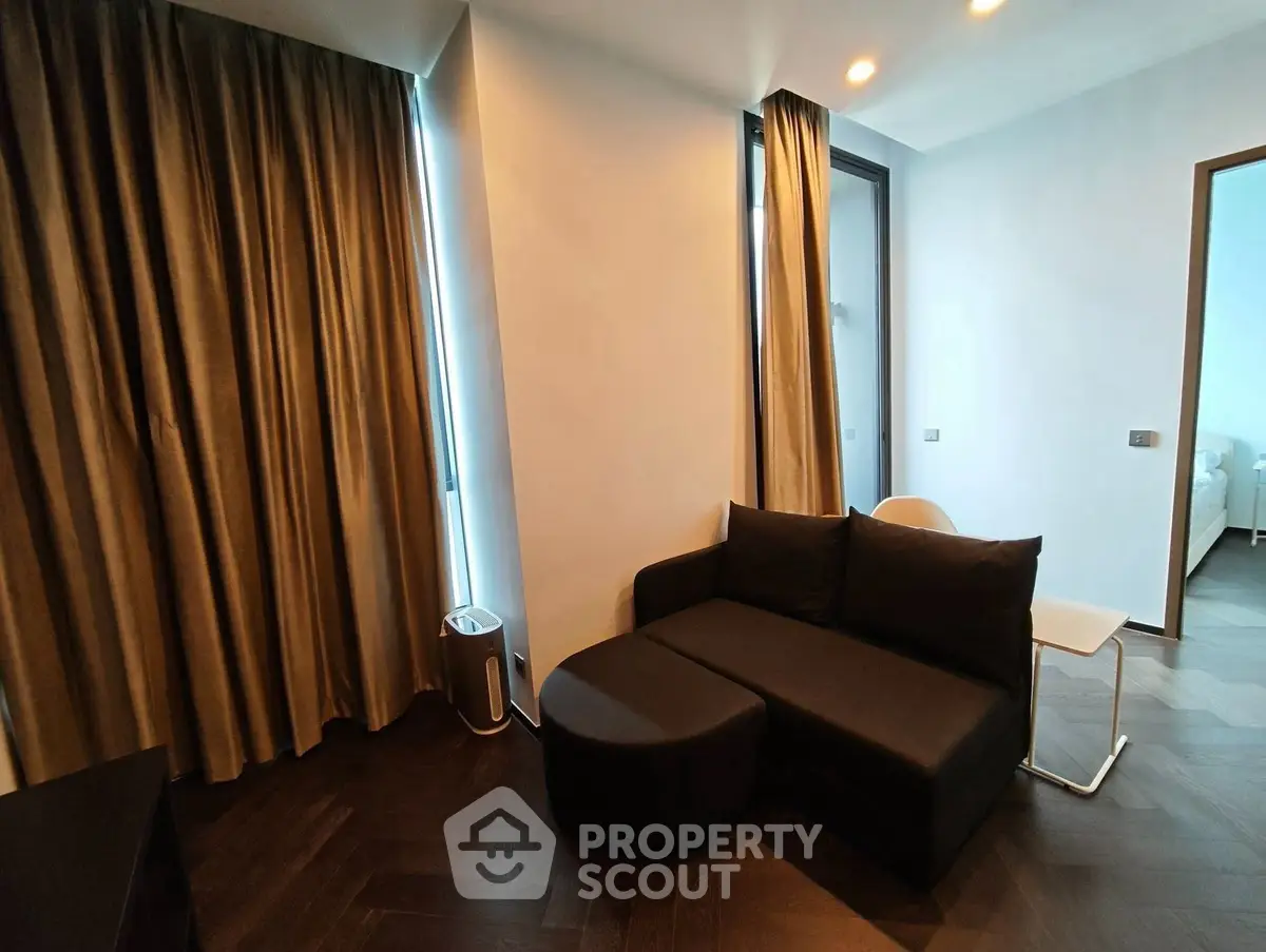 Modern living room with sleek black sofa and elegant curtains in a stylish apartment.