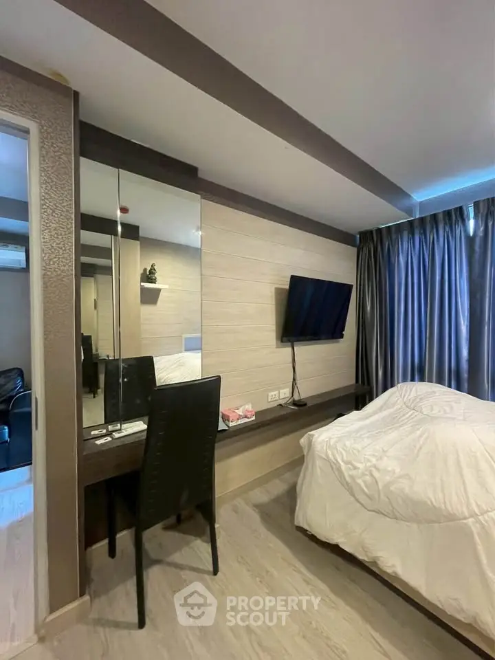 Modern bedroom with sleek design, featuring a wall-mounted TV and stylish desk area.