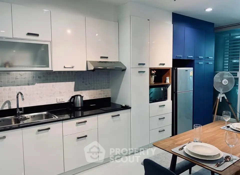 Modern kitchen with sleek cabinetry and dining area, featuring stainless steel appliances and elegant table setting.