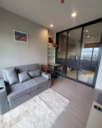 Modern living room with balcony view, featuring sleek furniture and stylish decor in a cozy apartment.