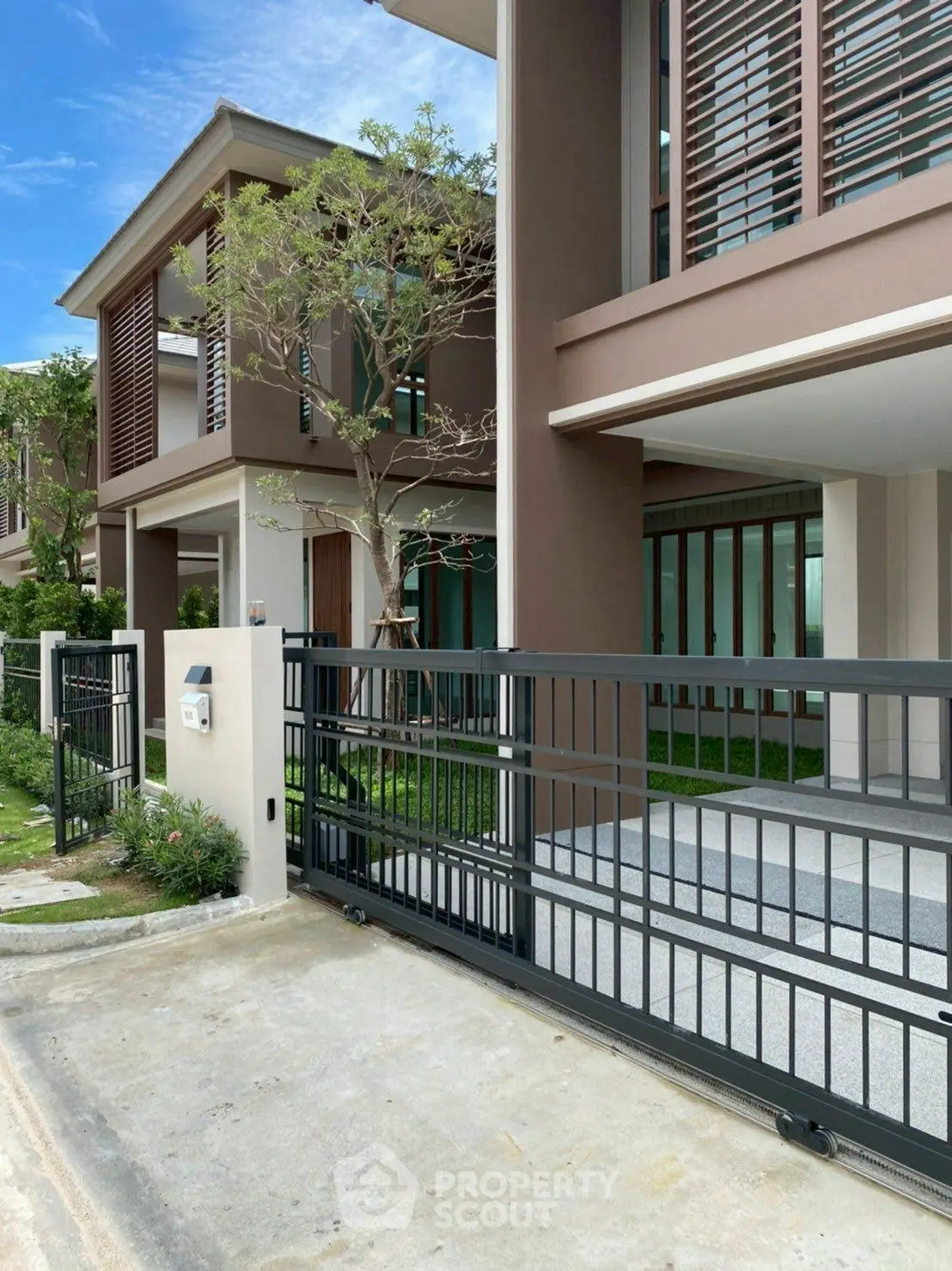 Modern townhouse exterior with sleek design and gated entrance in a serene neighborhood.