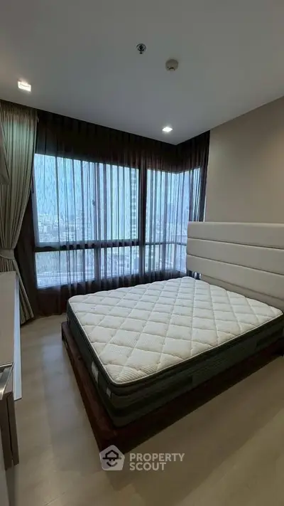 Spacious bedroom with large windows and modern decor in a high-rise apartment.