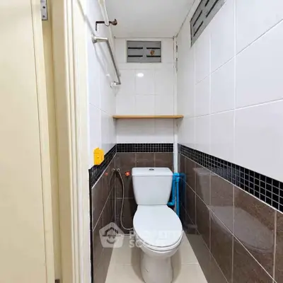 Compact bathroom with modern toilet and tiled walls in a cozy real estate unit.