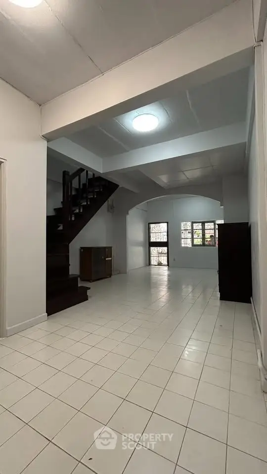 Spacious open-plan living area with staircase and large windows, perfect for modern family living.