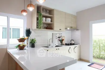 Modern kitchen with sleek countertops, open shelving, and natural light from large windows.