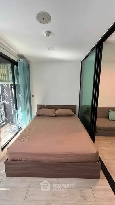 Modern bedroom with large glass doors and minimalist design, featuring a cozy bed and natural light.