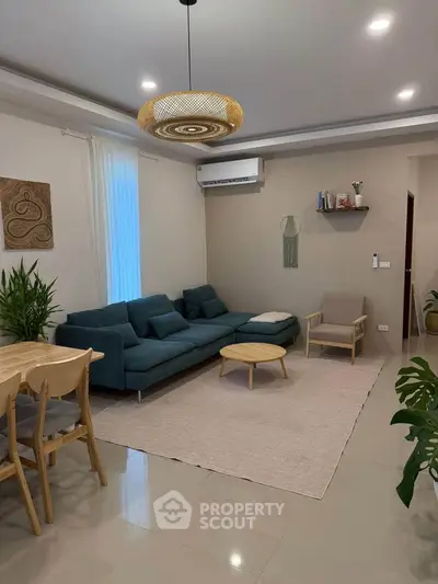 Modern living room with stylish decor, featuring a comfortable sofa, elegant lighting, and a cozy dining area.