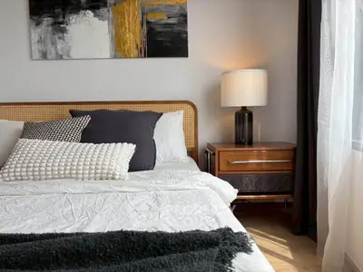 Cozy bedroom with stylish decor, featuring a modern lamp and elegant artwork above the bed.
