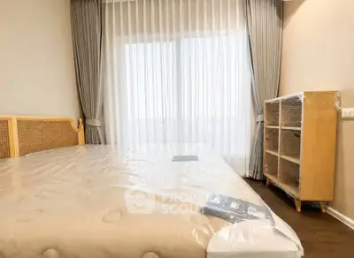 Spacious bedroom with elegant curtains and natural light, featuring a cozy bed and stylish wooden furniture.