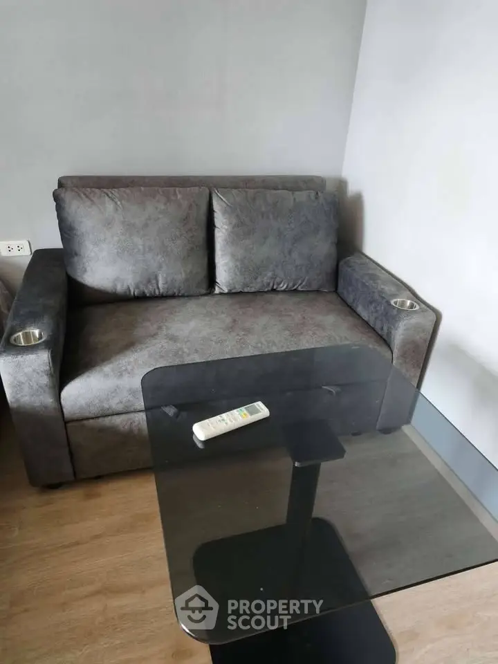 Cozy living room with plush gray sofa and sleek glass coffee table, perfect for modern apartment living.
