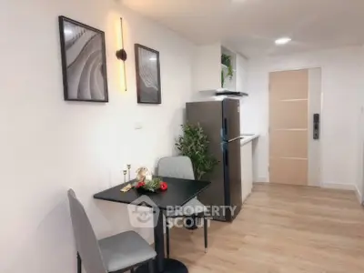 Modern kitchen with sleek design, featuring a compact dining area and stainless steel fridge.
