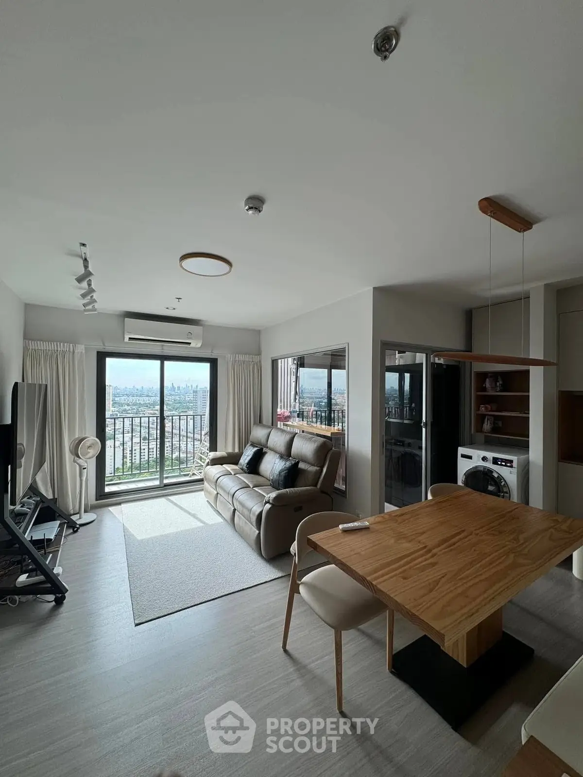 Modern living room with balcony view, stylish furniture, and open layout in a high-rise apartment.
