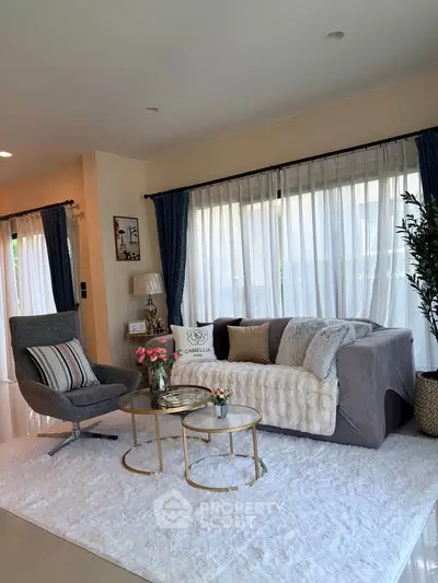 Elegant living room with cozy sofa, stylish armchair, and chic decor in a bright, airy space.