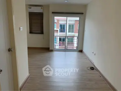 Spacious empty living room with balcony and wooden flooring in modern apartment.