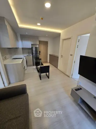 Modern open-layout living room with sleek kitchen and cozy seating area, perfect for urban living.