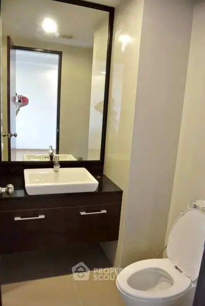 Modern bathroom with sleek vanity and large mirror in contemporary apartment.