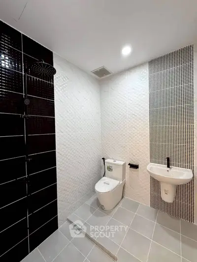 Modern bathroom with sleek black and white tile design and contemporary fixtures.