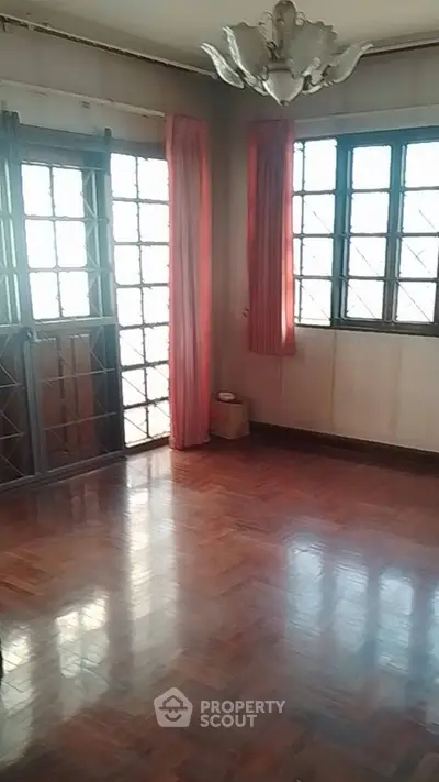 Spacious living room with wooden flooring and large windows for natural light.