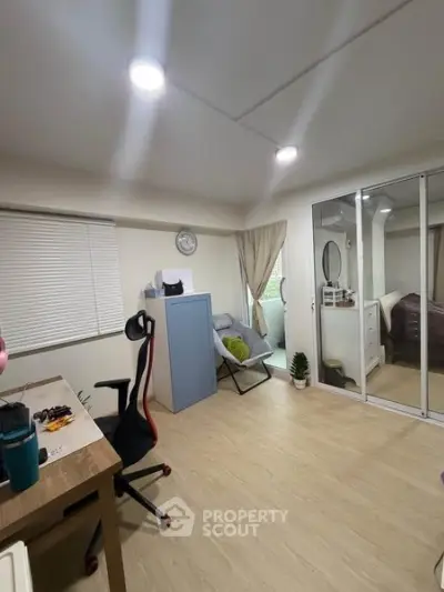 Modern bedroom with mirrored closet and cozy seating area, perfect for relaxation and productivity.