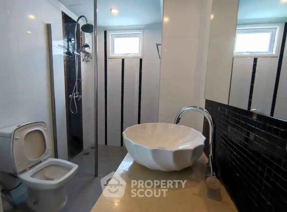 Modern bathroom with unique sink and shower area in stylish apartment.