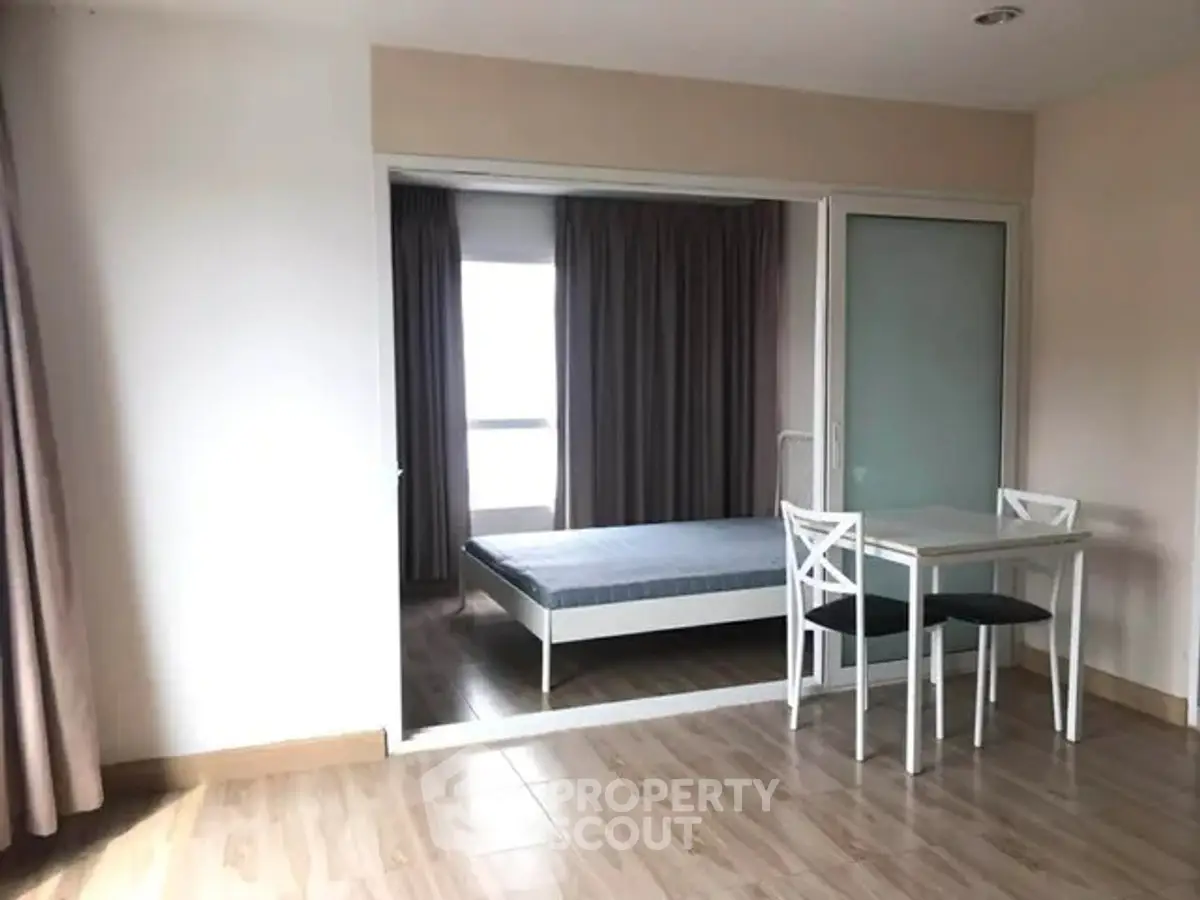 Spacious bedroom with wooden flooring and sliding glass doors in modern apartment.