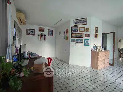 Spacious living area with tiled flooring and wall decor, featuring a desk and chest of drawers.