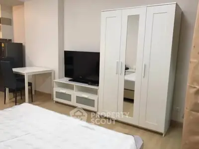 Modern bedroom with sleek white furniture and flat-screen TV, perfect for urban living.