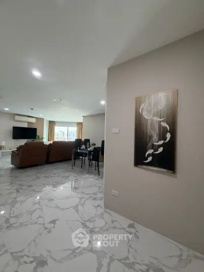 Spacious modern living room with marble flooring and elegant decor, featuring a large TV and comfortable seating.