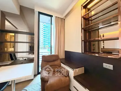Modern study room with plush recliner and built-in shelving, featuring large window with city view.