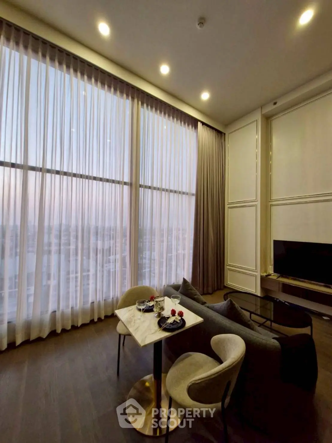 Luxurious high-ceiling living room with elegant decor and stunning city view.