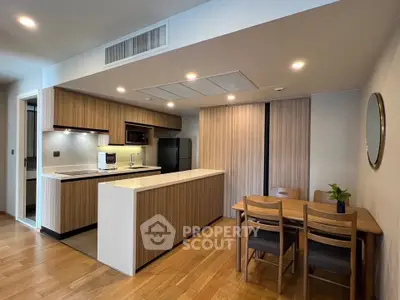 Modern kitchen with wooden cabinetry and dining area in open layout apartment.