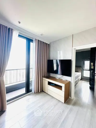 Modern living room with balcony access and sleek TV setup in a stylish apartment.