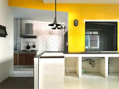 Spacious kitchen with vibrant yellow accent wall and modern fixtures