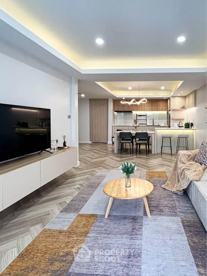 Modern open-plan living room with stylish kitchen, featuring sleek furniture and elegant lighting.