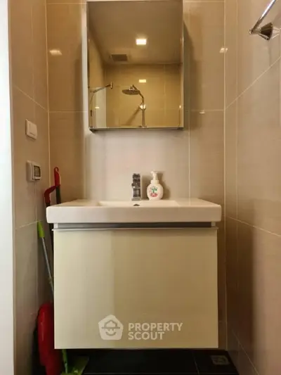 Modern bathroom with sleek vanity and mirror, featuring neutral tiles and elegant fixtures.