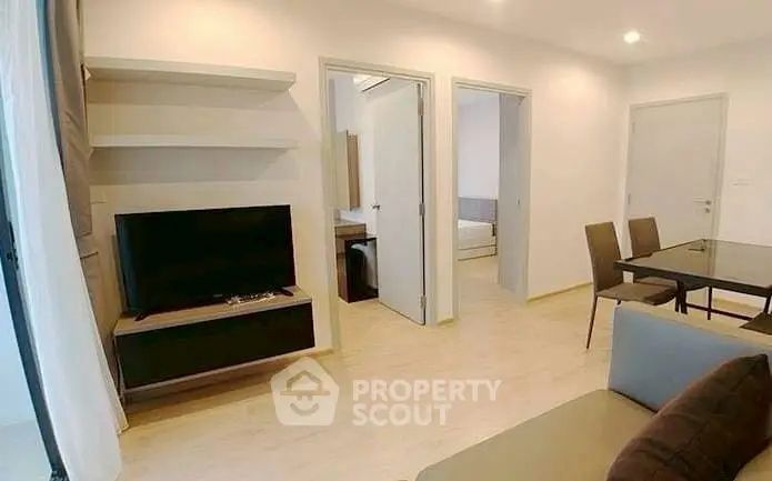 Modern living room with sleek TV setup and dining area in open layout apartment.