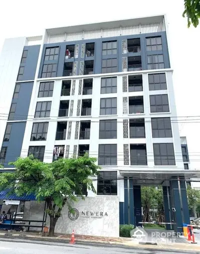 Modern urban apartment building with sleek facade, featuring large windows and a prominent entrance, ideal for city living.