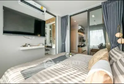 Modern bedroom with large TV and stylish decor, featuring natural light and elegant curtains.